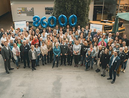 Gruppenbild mit Menschen und Luftballons die die Zahl 86.000 zeigen